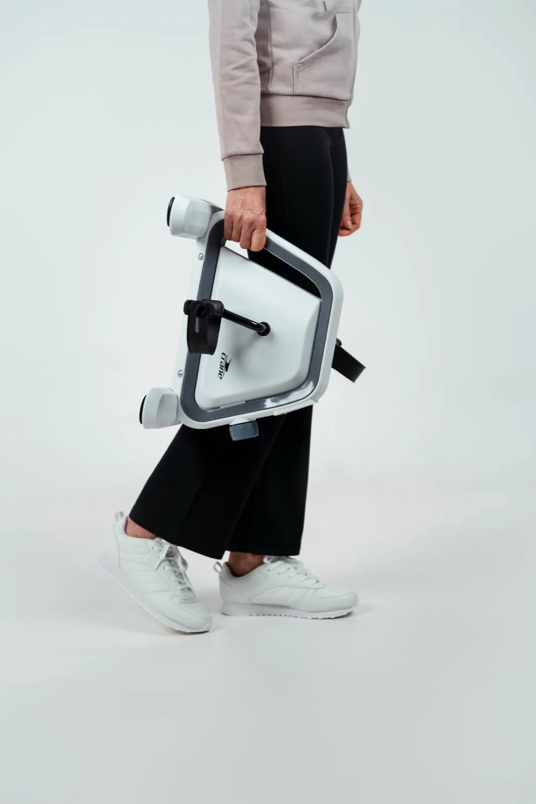 ALDI – Eine Person trägt ein kompaktes, weißes Heimtrainer-Pedalgerät in einem Fotostudio