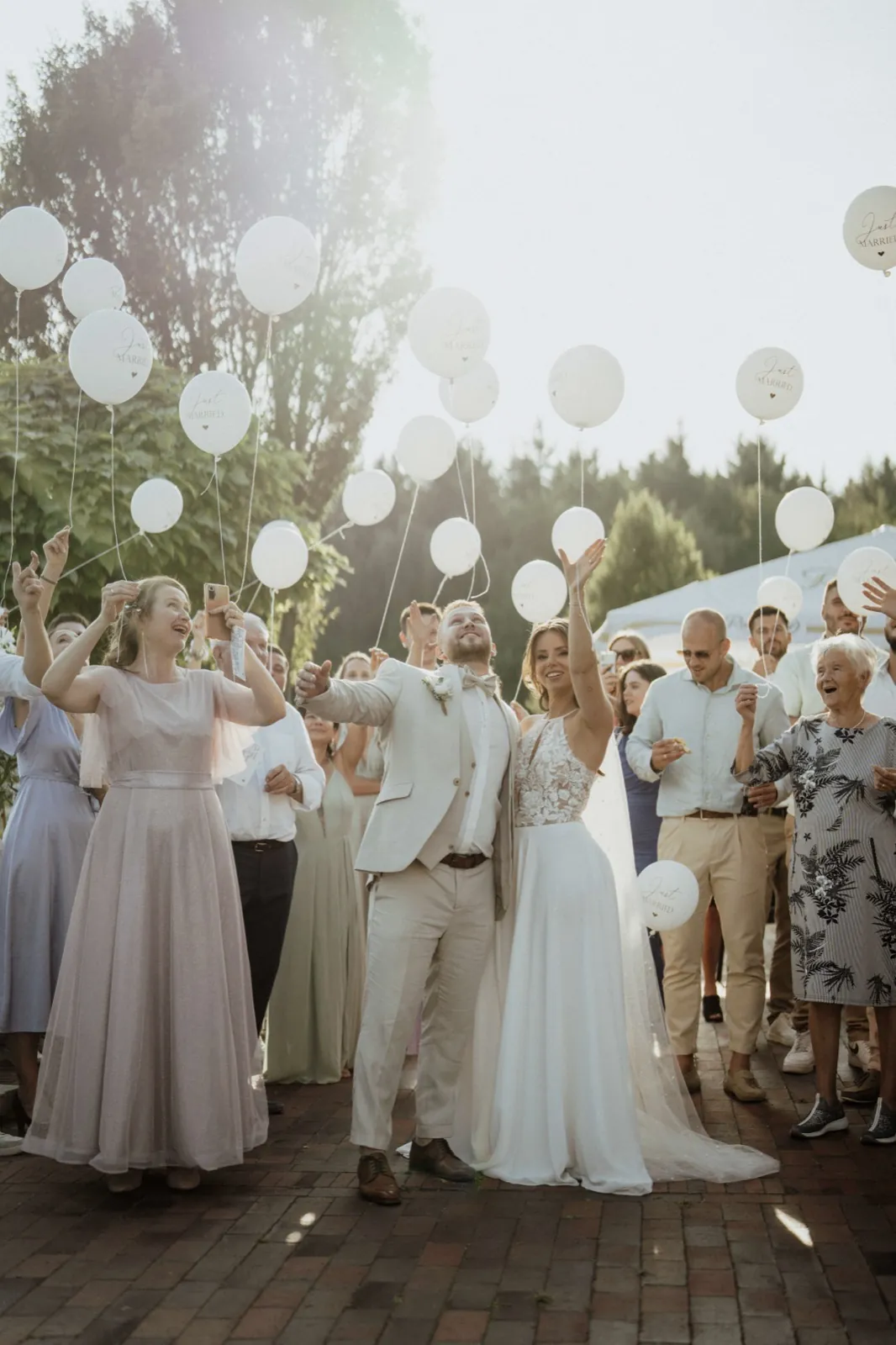 Anna & Moritz – Brautpaar und Gäste lassen weiße Luftballons im Freien steigen