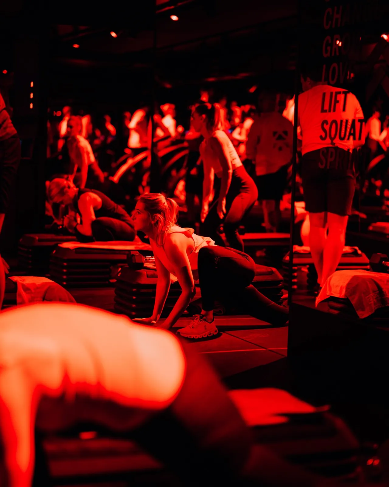 Barry's Frankfurt – Menschen trainieren in einem Fitnessstudio unter intensivem rotem Licht auf Steppbrettern