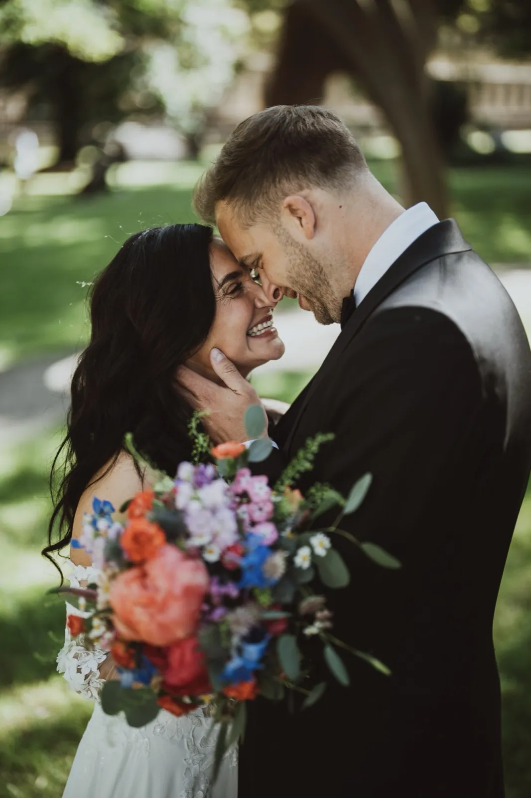 Caro & Dominik – Ein Brautpaar steht eng umschlungen im Freien und lächelt sich glücklich an