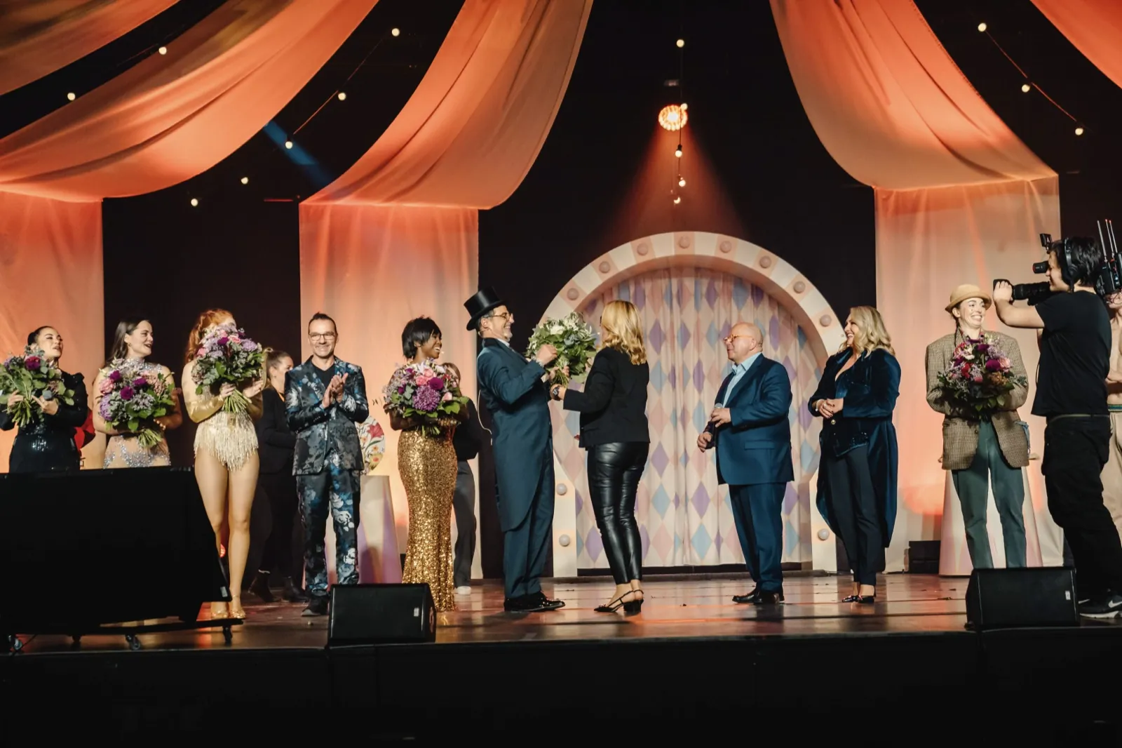Cirque Inspiré – Eine Gruppe von Künstlern steht nach einer Show mit Blumensträußen auf einer Bühne