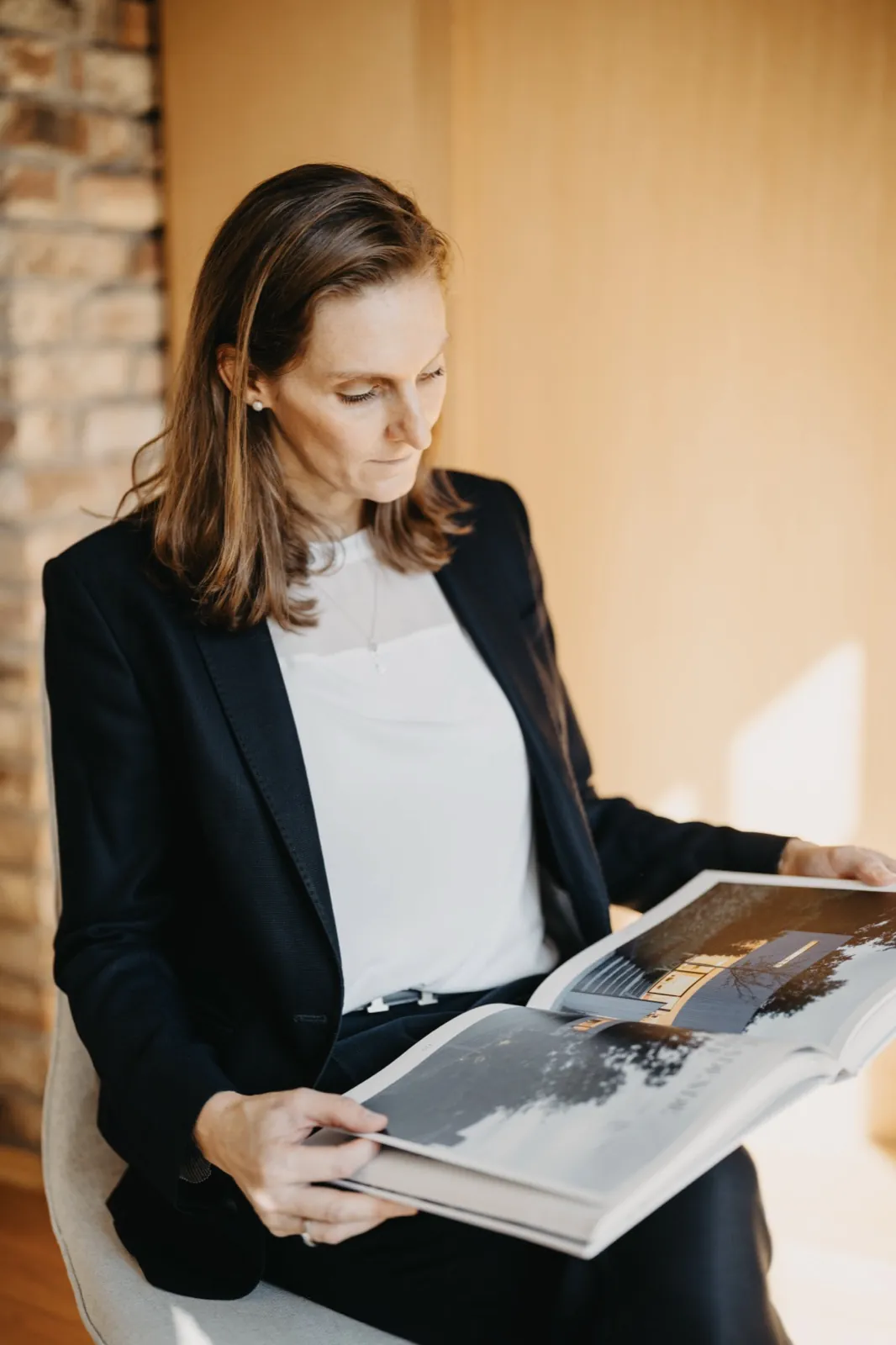 Franziska Hildenbrandt – Eine Frau im schwarzen Blazer sitzt auf einem Stuhl und schaut in ein Buch