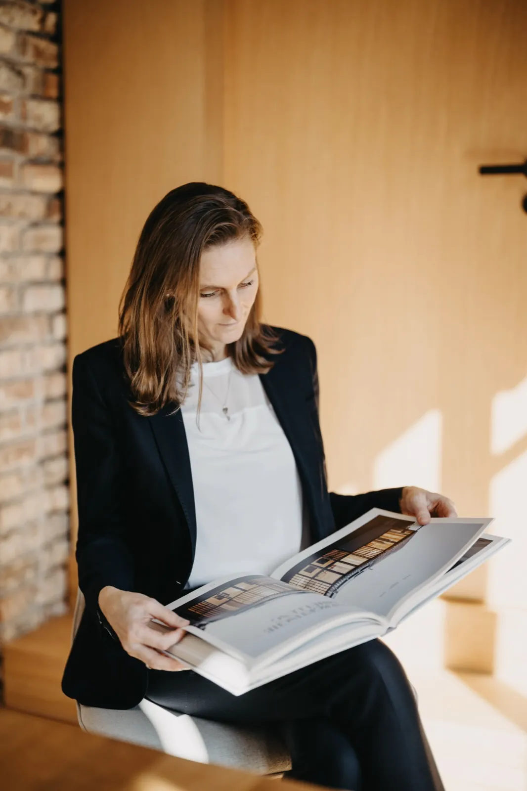 Franziska Hildenbrandt – Eine Frau im Business-Outfit sitzt auf einem Stuhl und schaut konzentriert in ein Buch