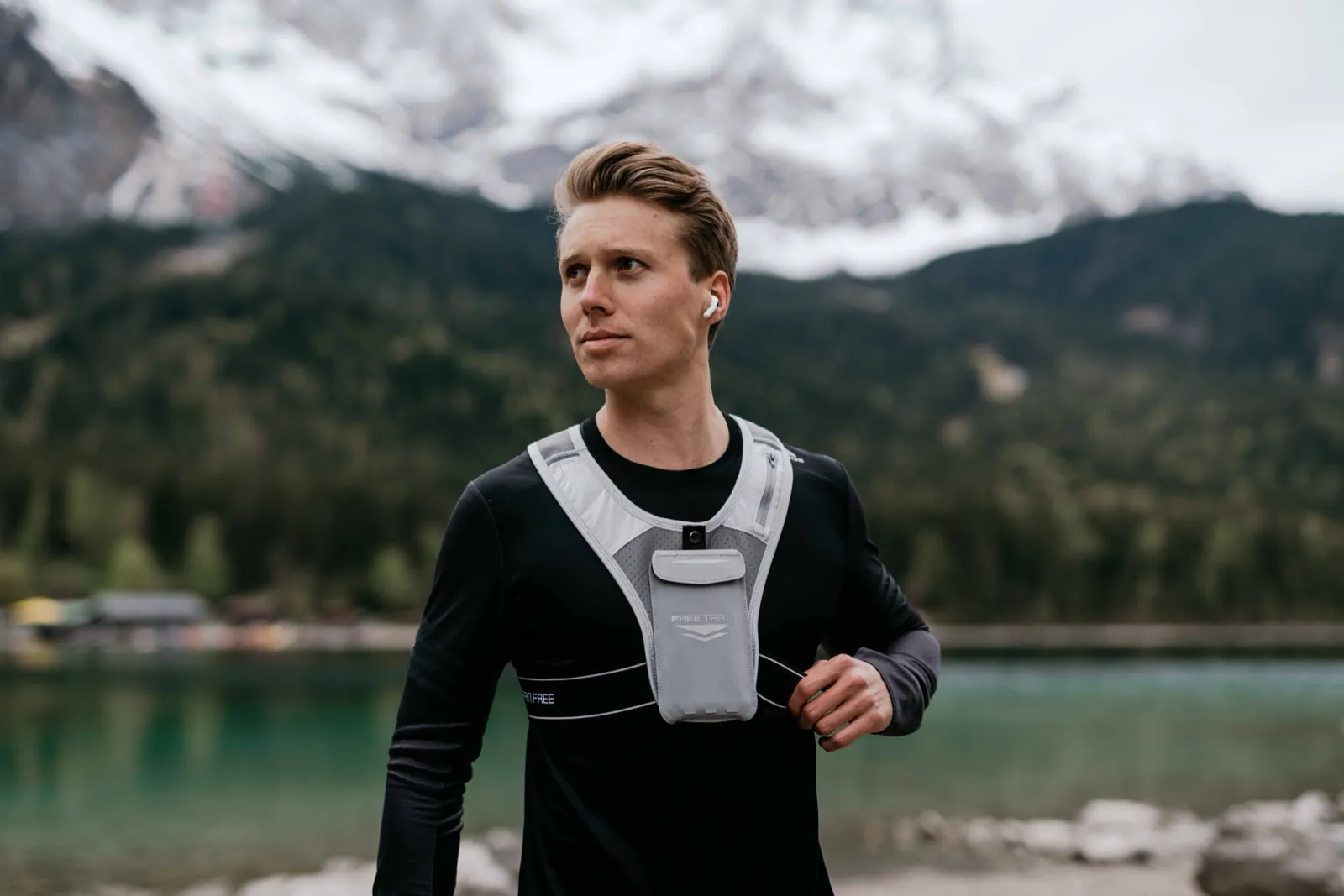 Freetrain – Ein junger Mann in Sportkleidung steht vor einer Bergkulisse an einem See