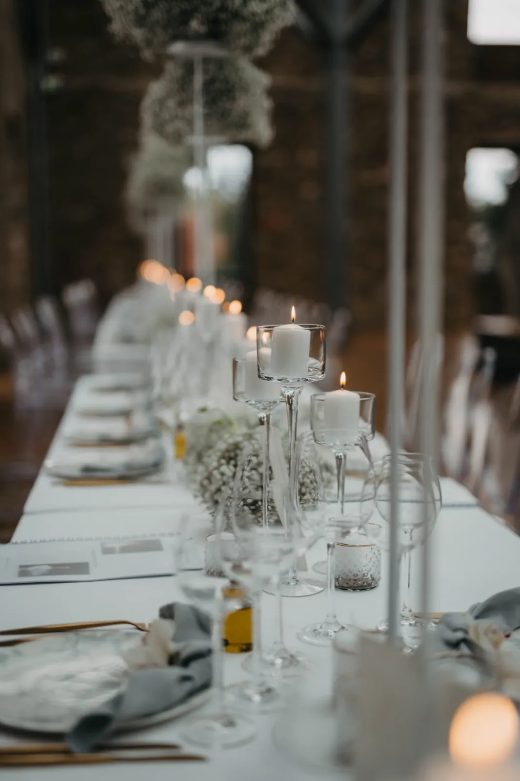 Imy & Felix – Eine festlich gedeckte Hochzeitstafel mit brennenden Kerzen und floraler Dekoration