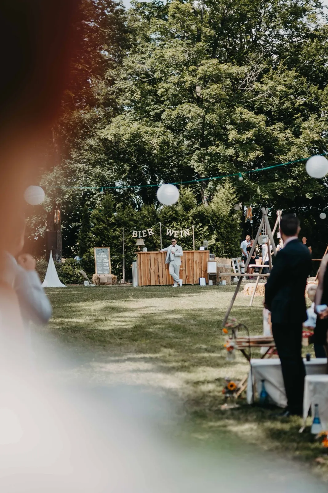 Jana & Christoph – Eine Hochzeitsgesellschaft im Freien an einer Bar mit der Aufschrift Bier und Wein