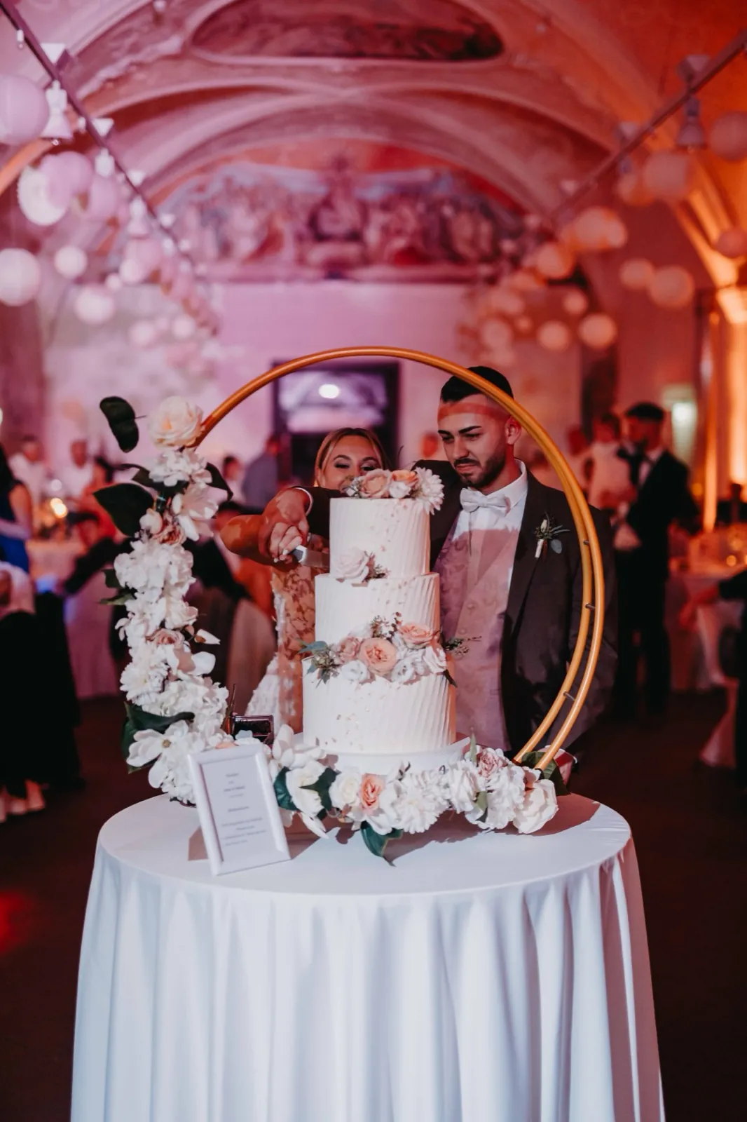 Jana & Daniel – Ein Brautpaar schneidet gemeinsam die dreistöckige Hochzeitstorte an