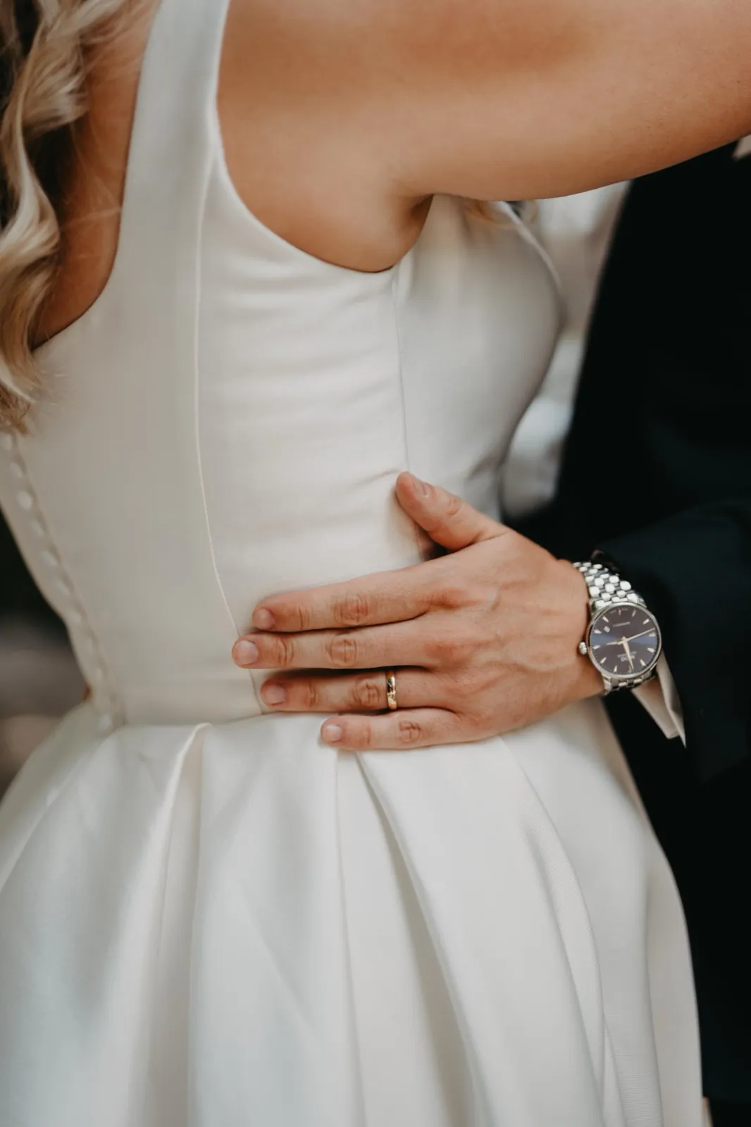 Janina & Alexander – Nahaufnahme der Hand des Bräutigams mit Ehering auf der Taille der Braut