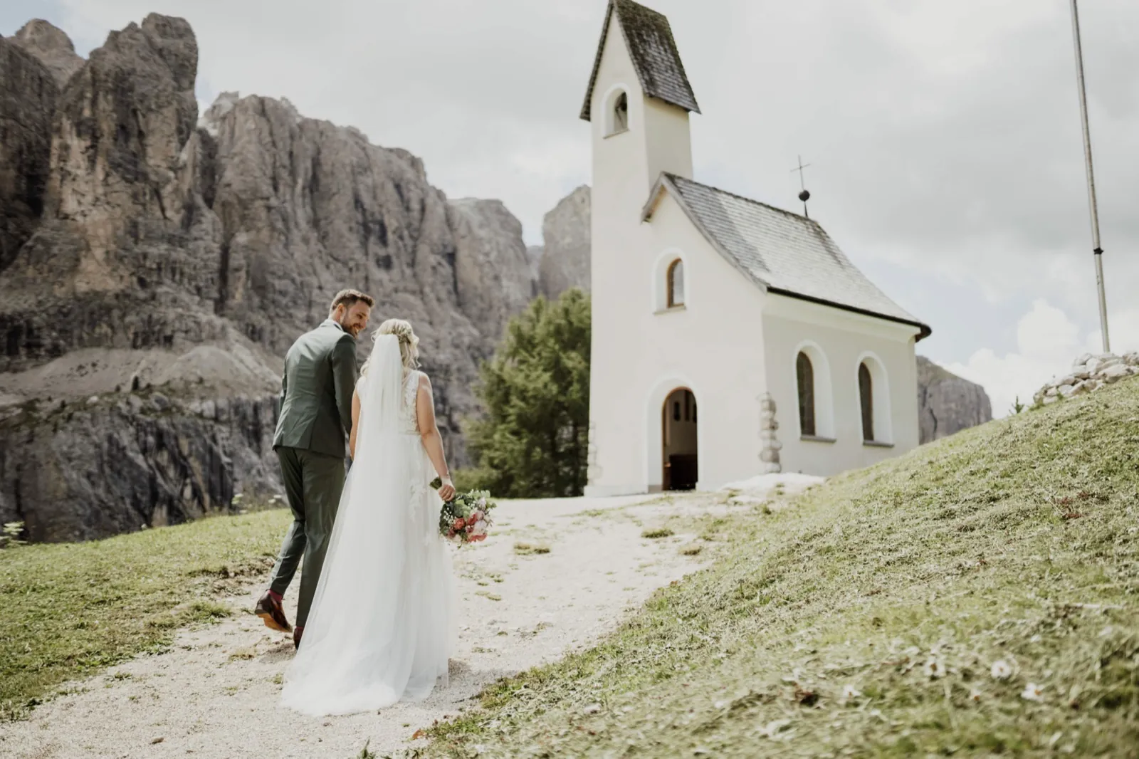 Katrin & Markus – Ein Brautpaar geht auf eine kleine Kapelle in einer bergigen Landschaft zu