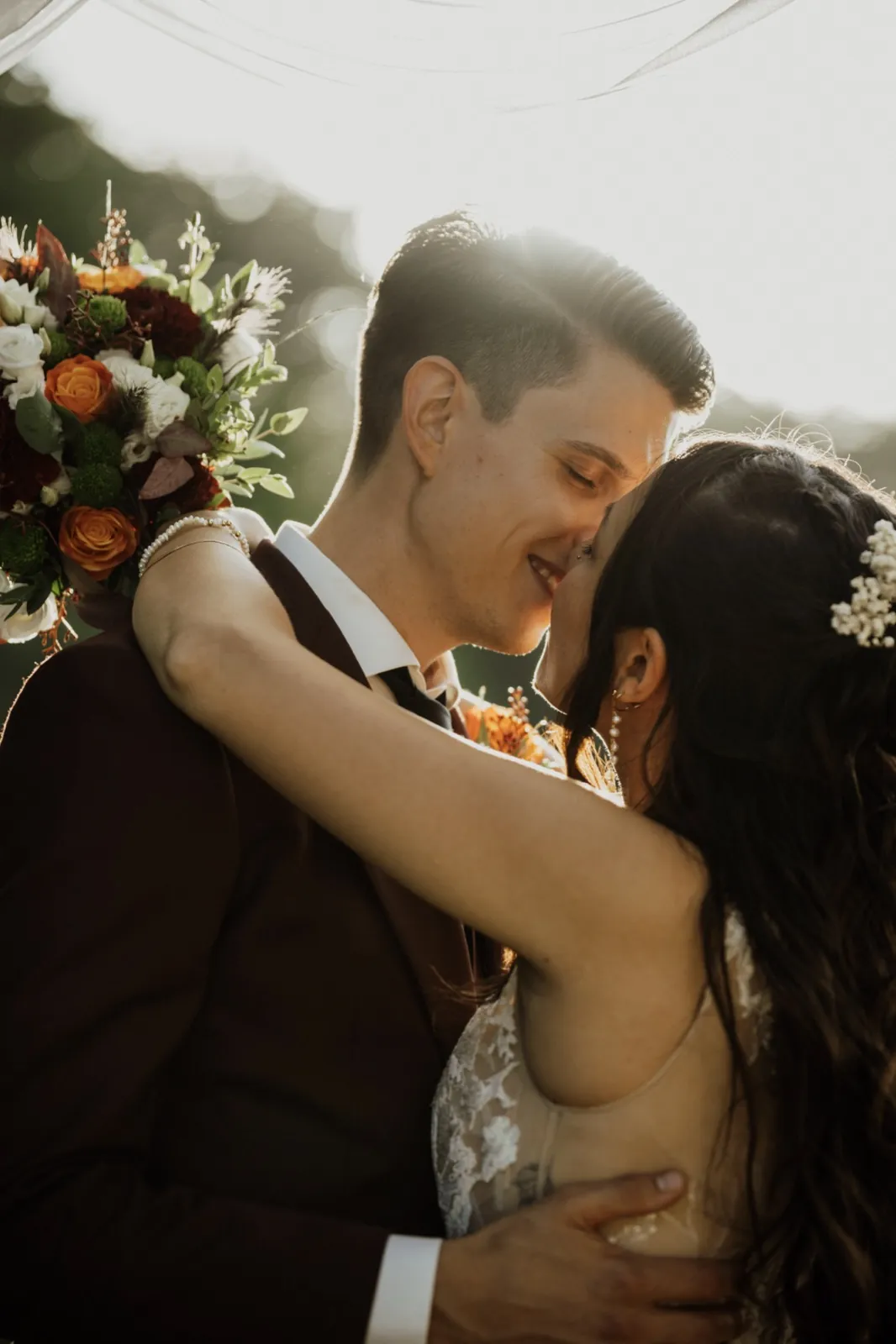 Marie & Thomas – Ein Brautpaar umarmt sich innig im warmen Gegenlicht