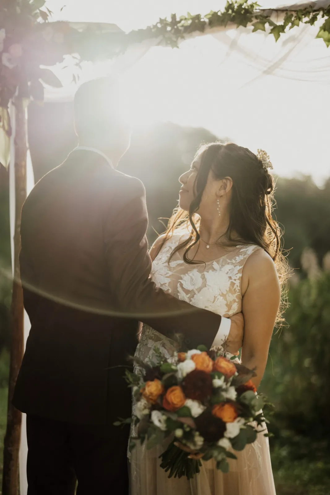 Marie & Thomas – Ein Brautpaar steht im Gegenlicht der Abendsonne eng beieinander und schaut sich an