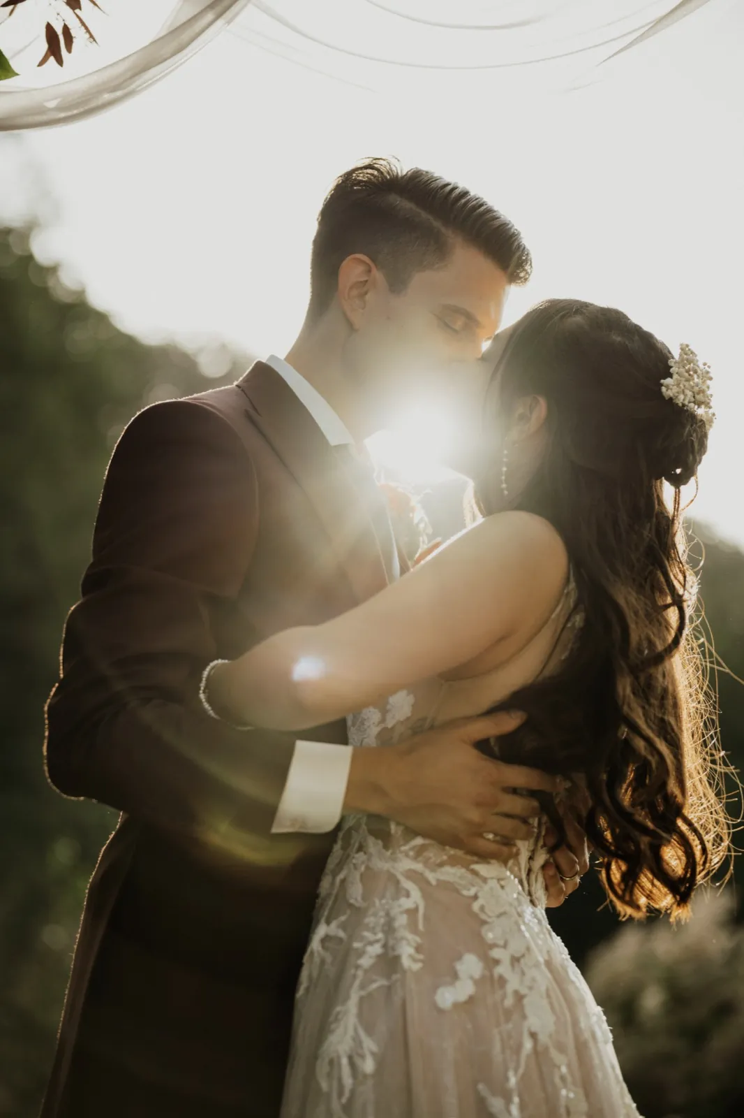 Marie & Thomas – Ein Brautpaar küsst sich im warmen Gegenlicht der Abendsonne im Freien