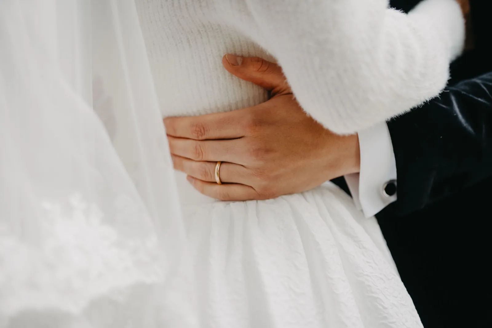 Mia & Clemens – Nahaufnahme der Hand des Bräutigams mit Ehering an der Taille der Braut