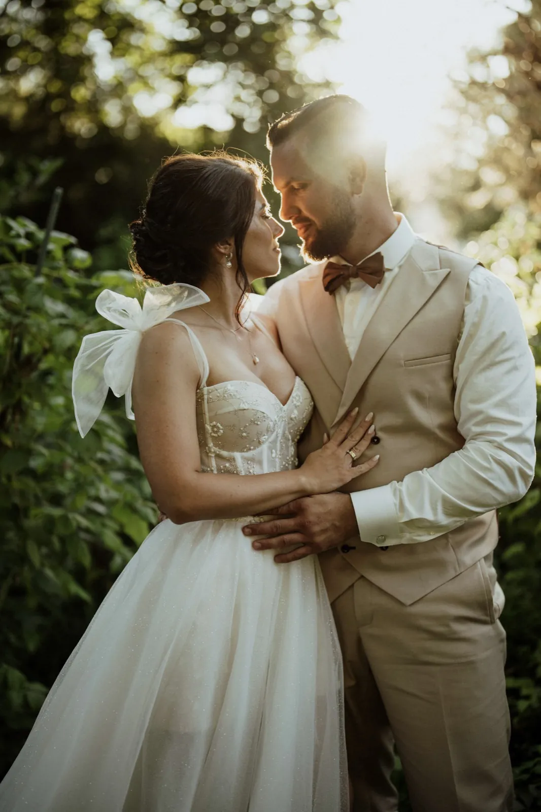 Nadine & Raphael – Ein Brautpaar steht eng umschlungen im warmen Gegenlicht im Freien