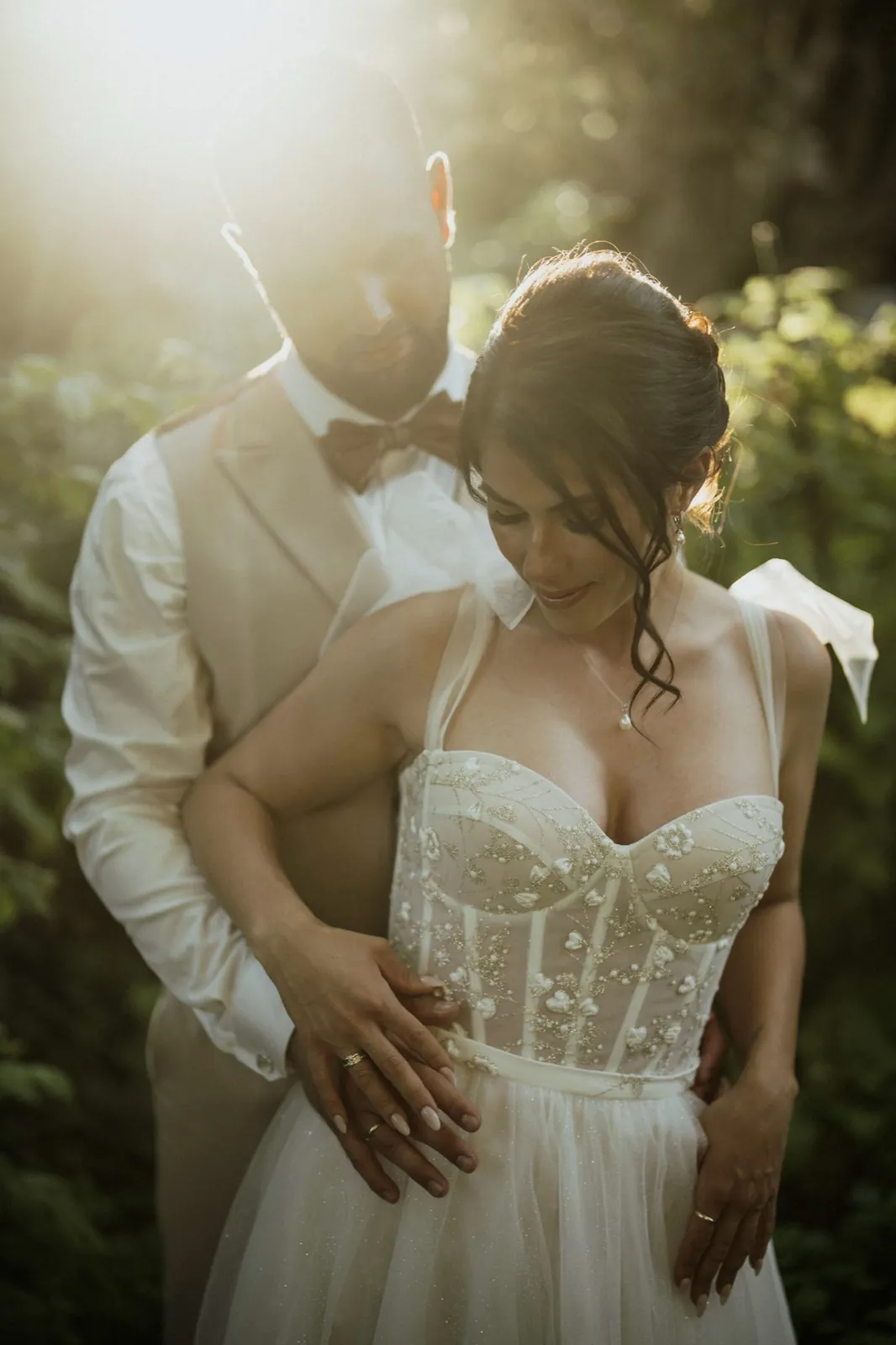Nadine & Raphael – Ein Brautpaar umarmt sich innig im warmen Gegenlicht im Freien