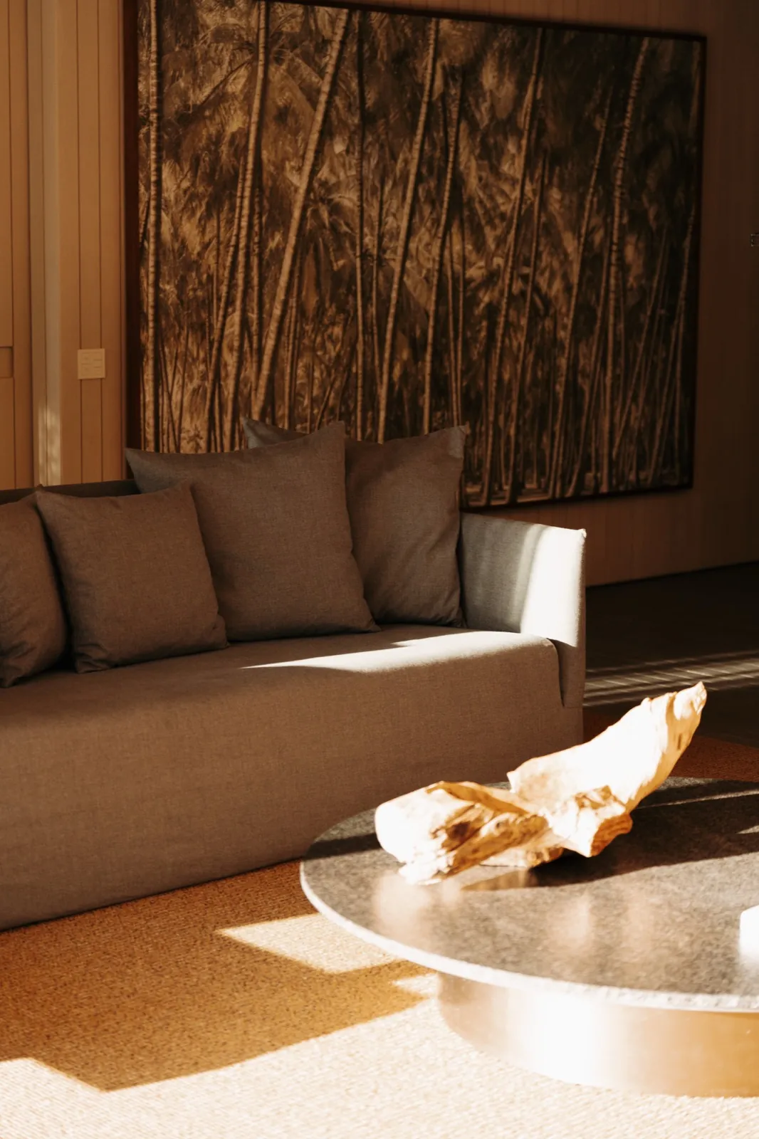 Patina Maldives – Ein modern eingerichteter Innenraum mit einem grauen Sofa, einem Couchtisch und einem großen Palmenbild