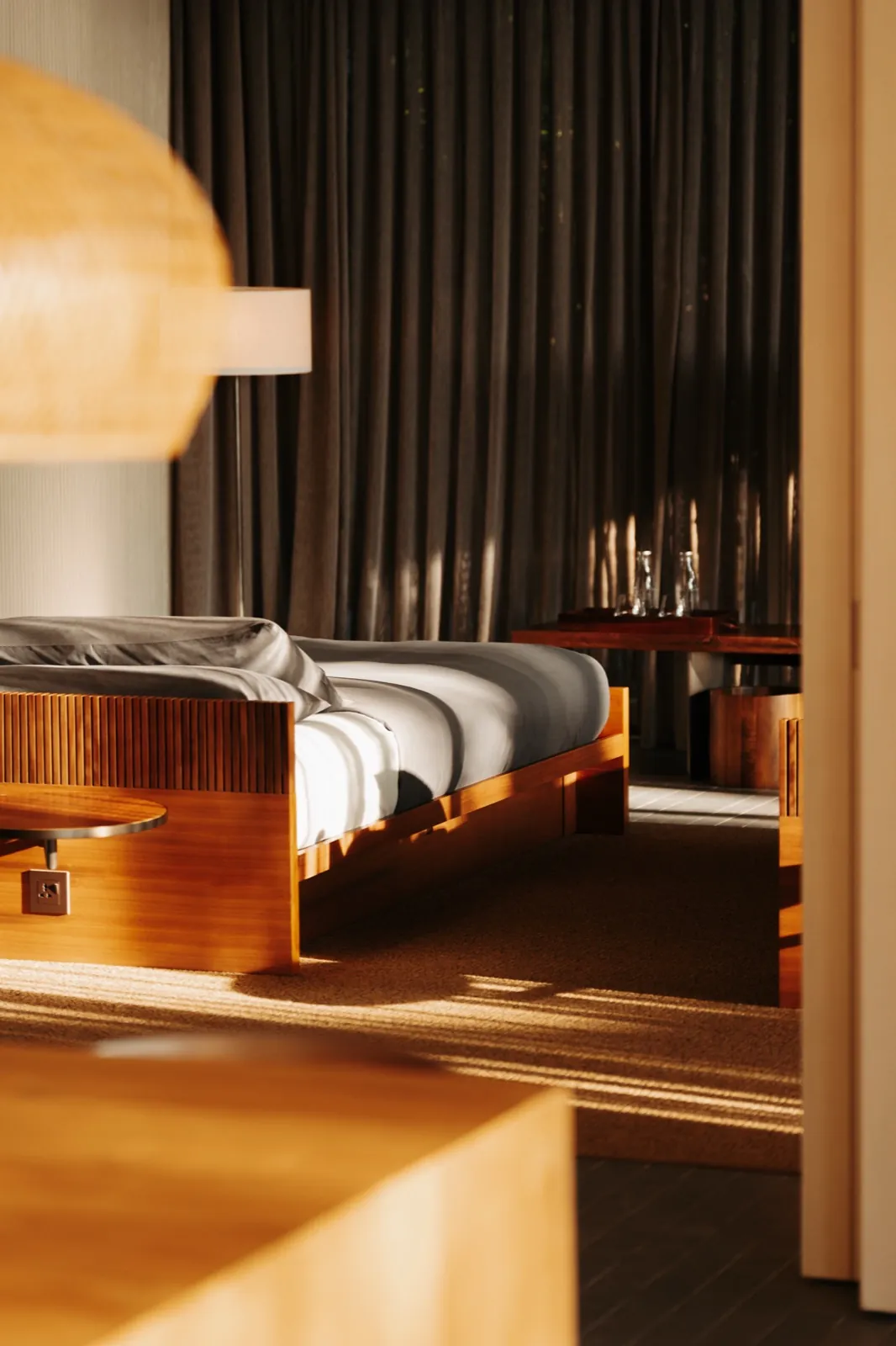 Patina Maldives – Ein modern eingerichtetes Schlafzimmer mit einem Holzbett im warmen Sonnenlicht