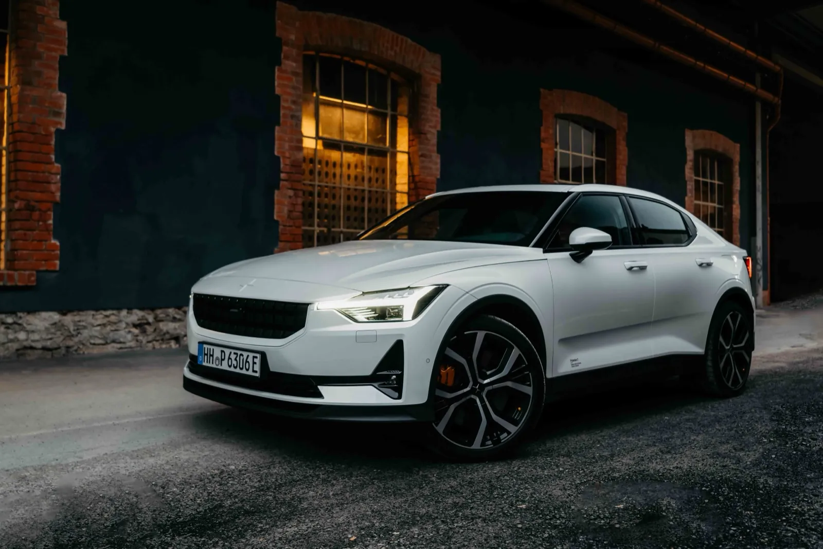 Polestar – Ein weißes Elektroauto steht vor einem dunklen Gebäude mit Backsteinfenstern
