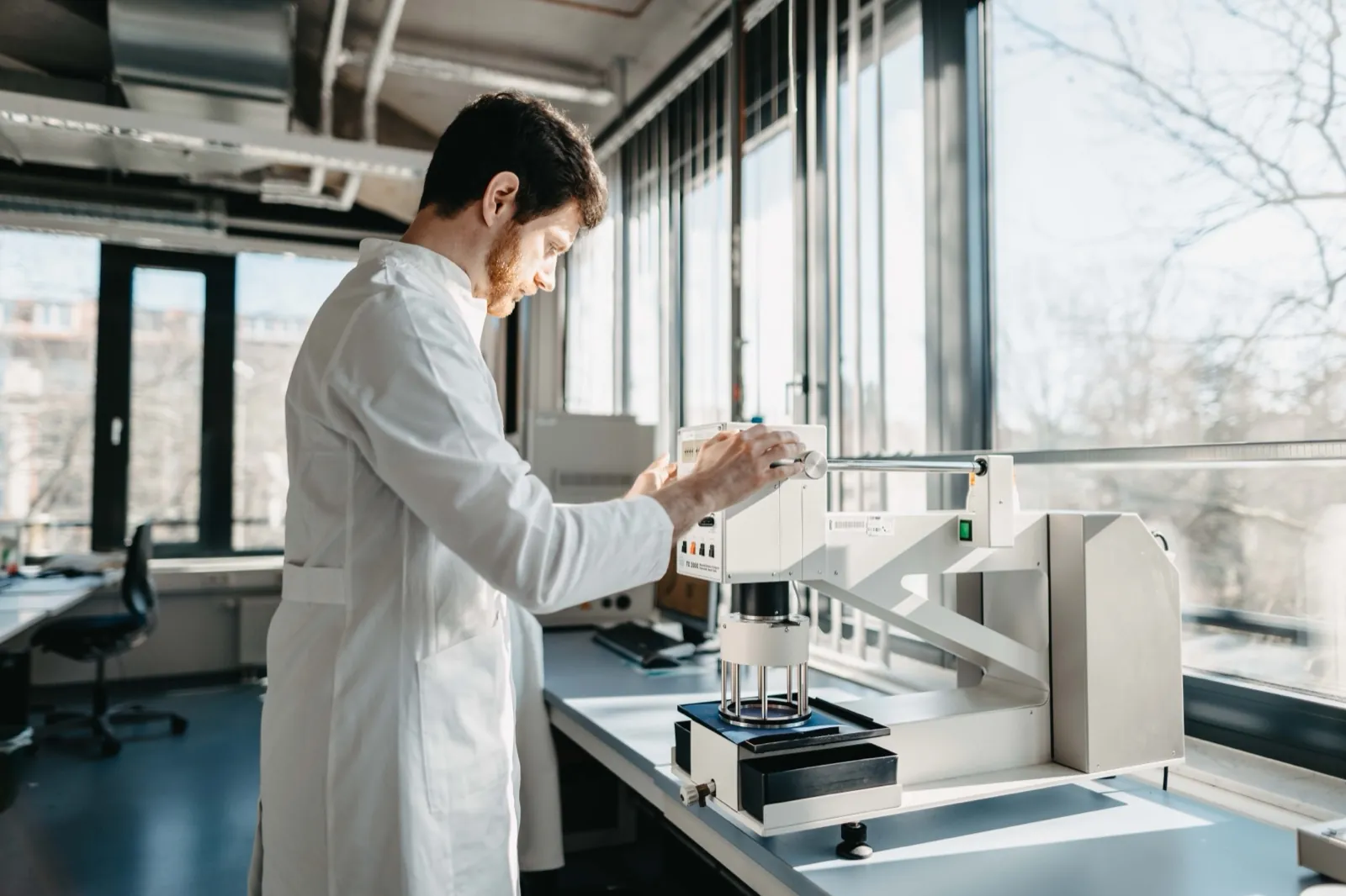 QIMA – Ein Wissenschaftler im weißen Kittel bedient ein Messgerät in einem hellen Labor
